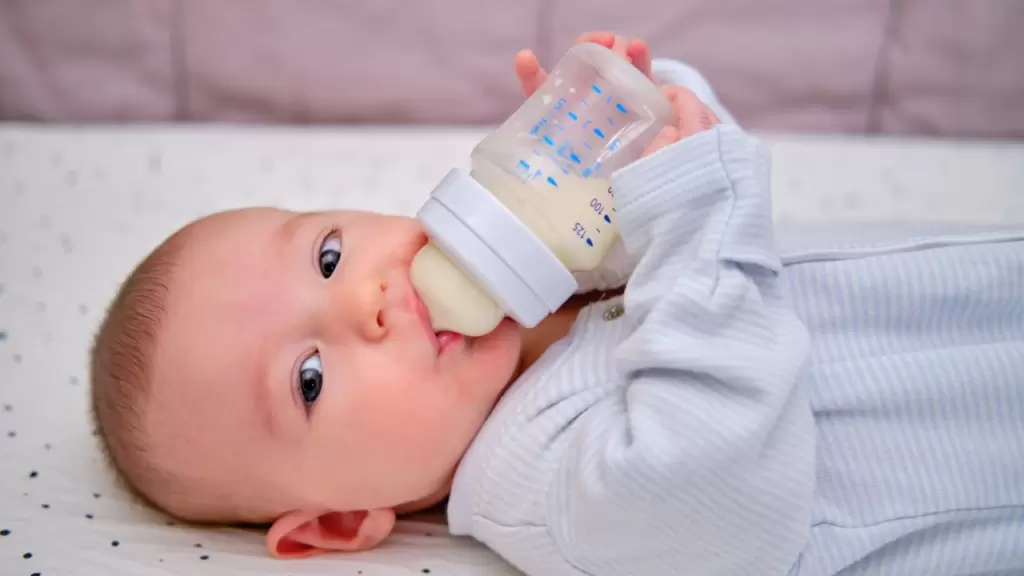 baby drinking breast milk in bottle